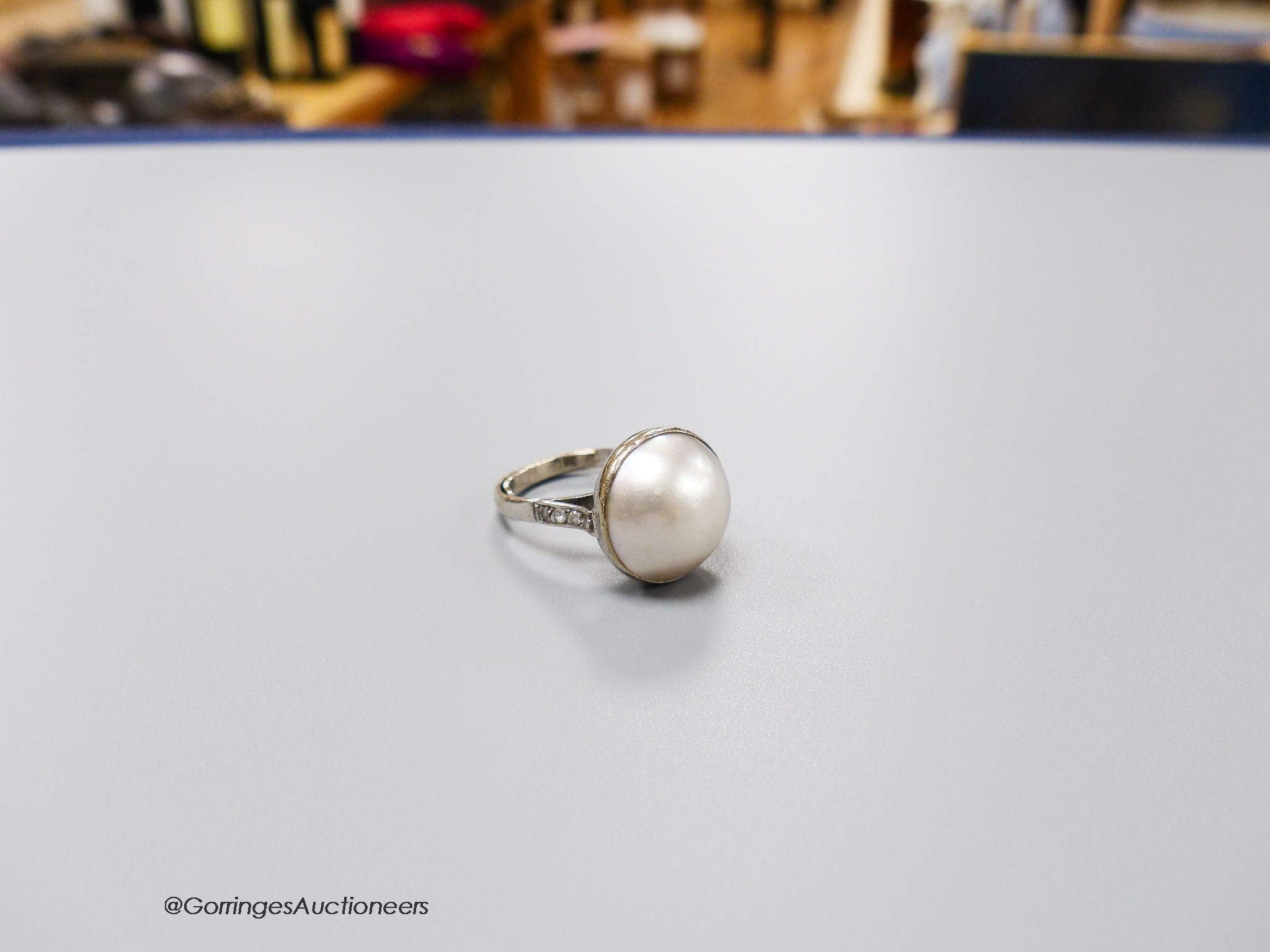 An 18ct white metal and mabe pearl set dress ring with diamond set shoulders, size N, gross 7.2 grams.